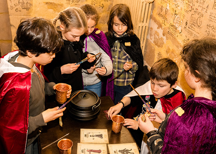 Enfants en capes utilisant des baguettes magiques autour d'un chaudron