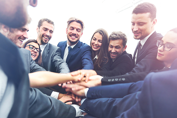 Groupe de collègues en costume empilant leurs mains pour team building