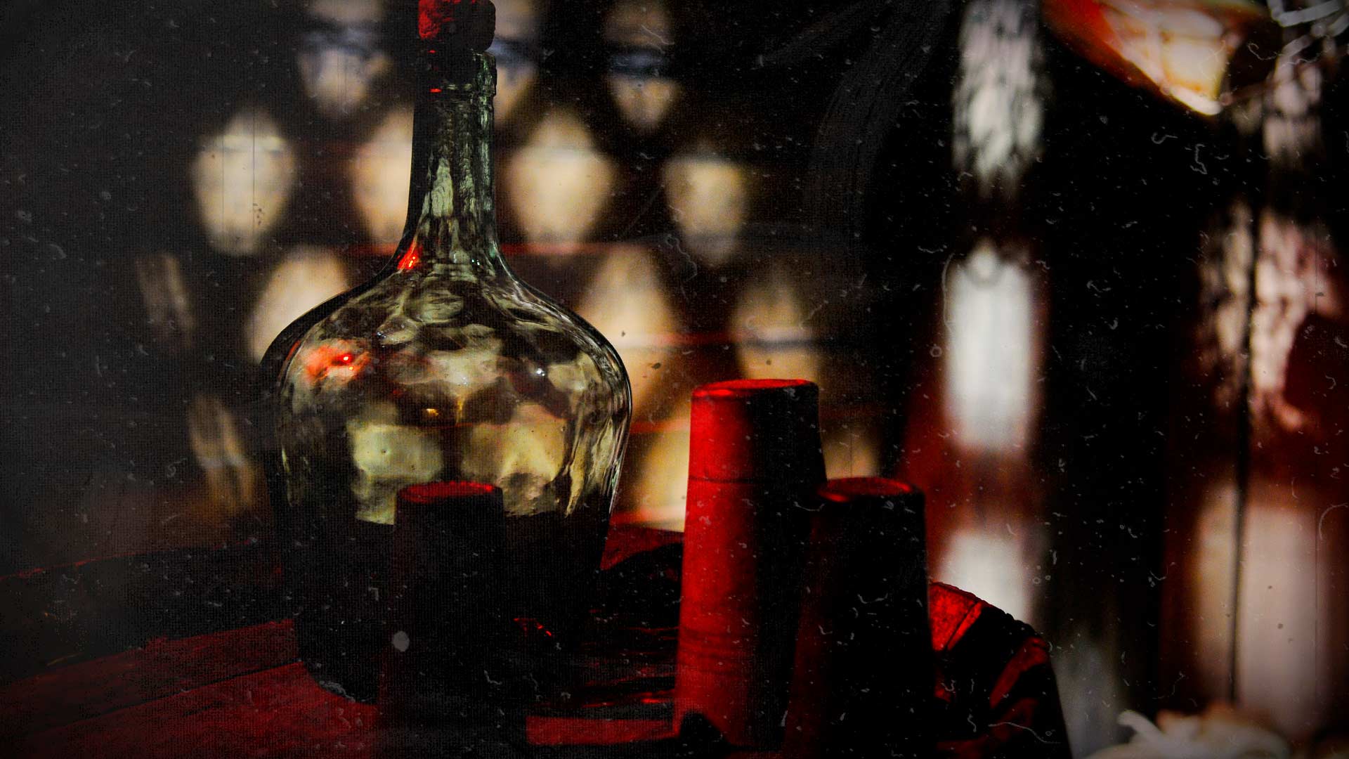 Bouteille en verre et bougies rouges dans une ambiance pirate sombre