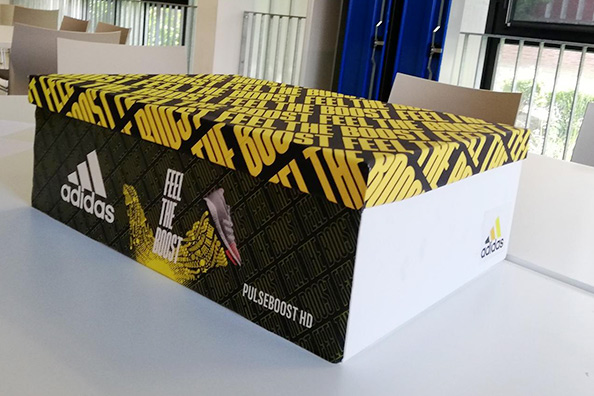 Boîte à chaussures Adidas noire et jaune posée sur une table