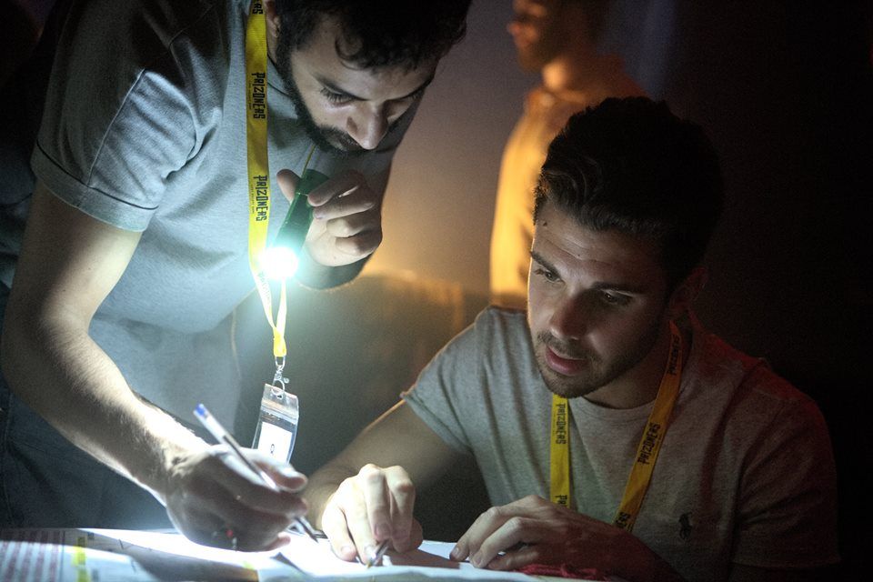 Joueurs utilisant une lampe torche pour résoudre une énigme d'escape game