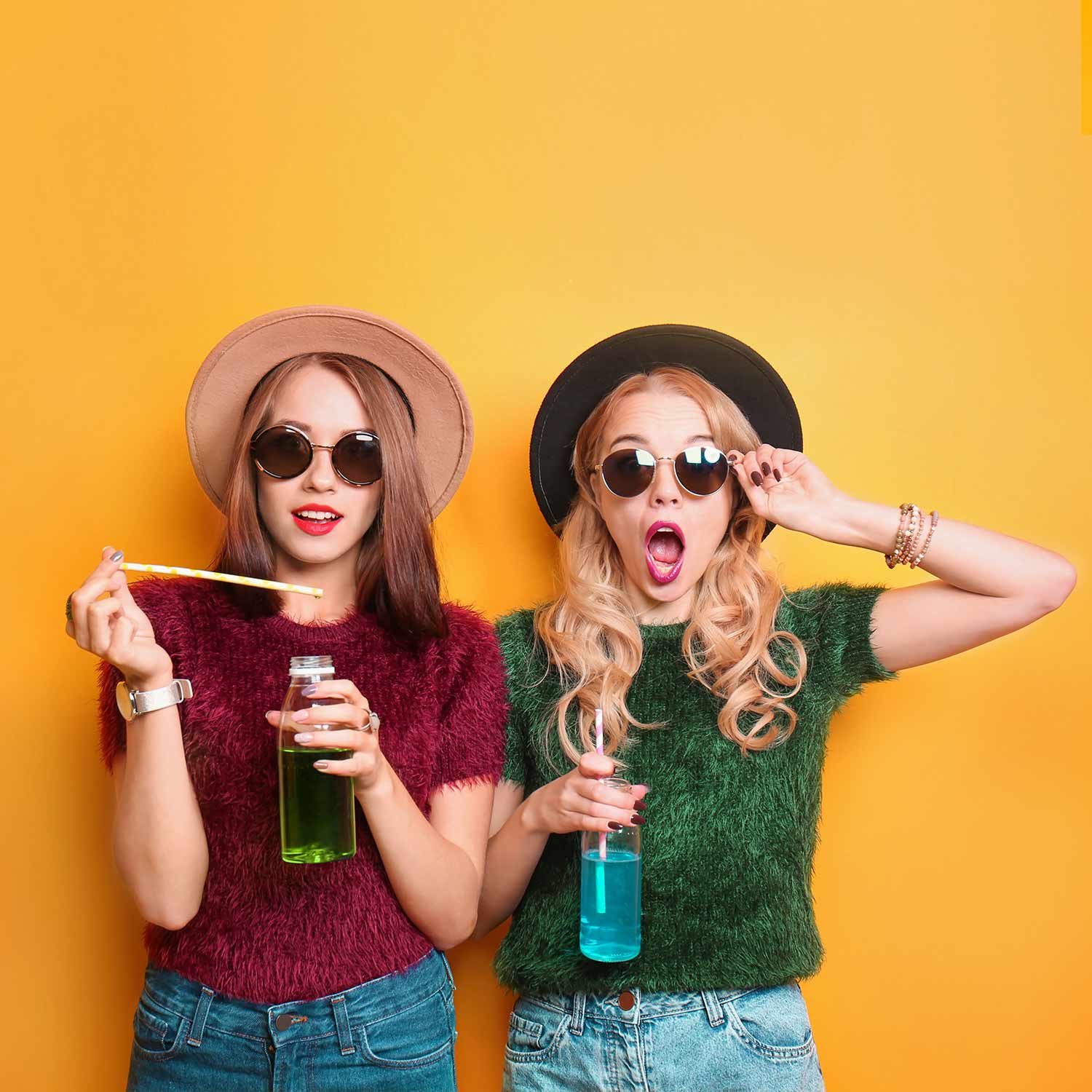 Deux jeunes femmes stylées avec lunettes de soleil et boissons colorées